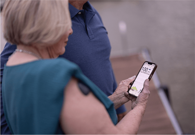 An older women checks her smartphone to monitor glucose levels